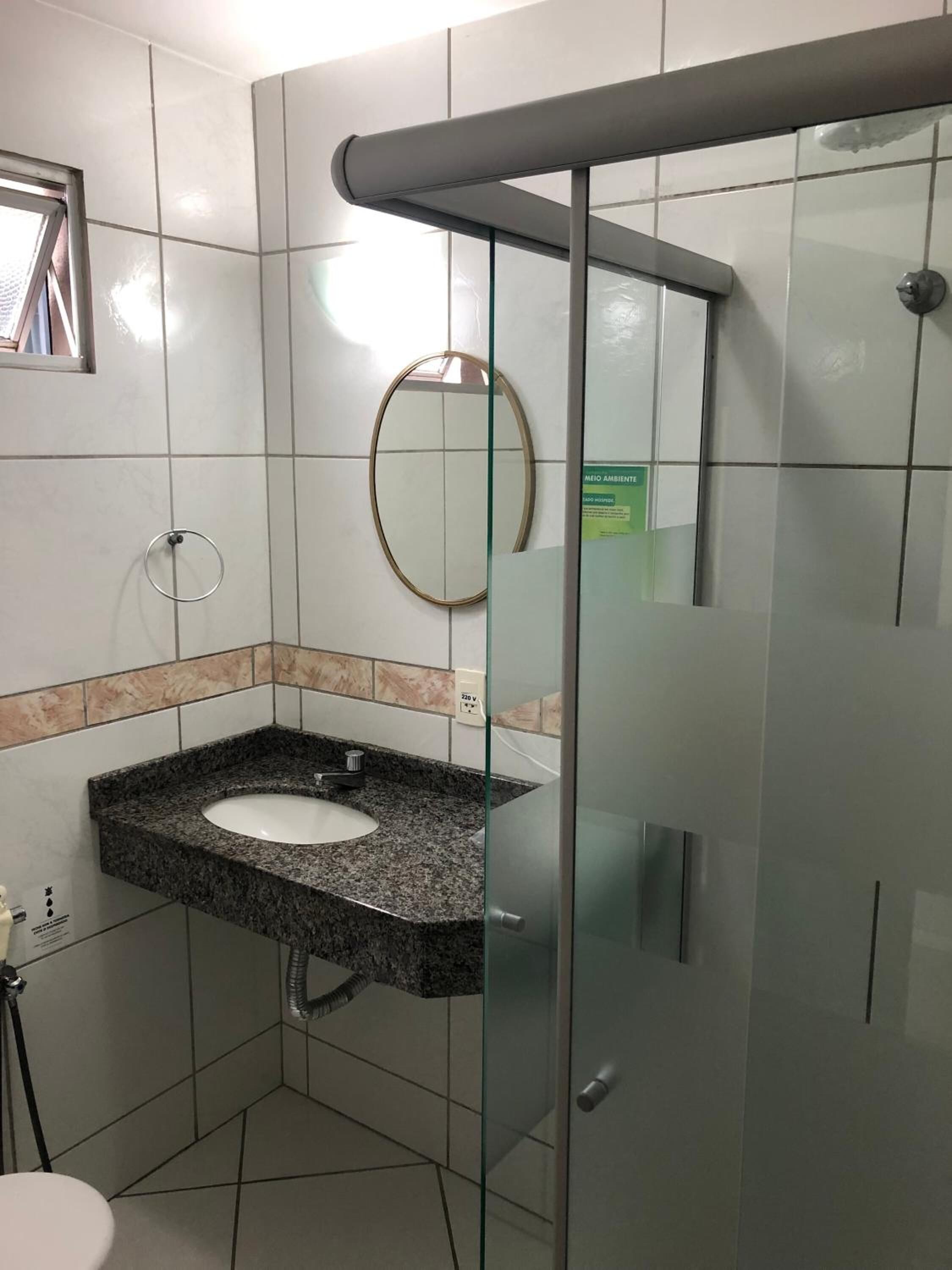 Un baño moderno con lavamanos de granito, cabina de ducha de vidrio y espejo en la pared.