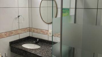 Un baño moderno con lavamanos de granito, cabina de ducha de vidrio y espejo en la pared.