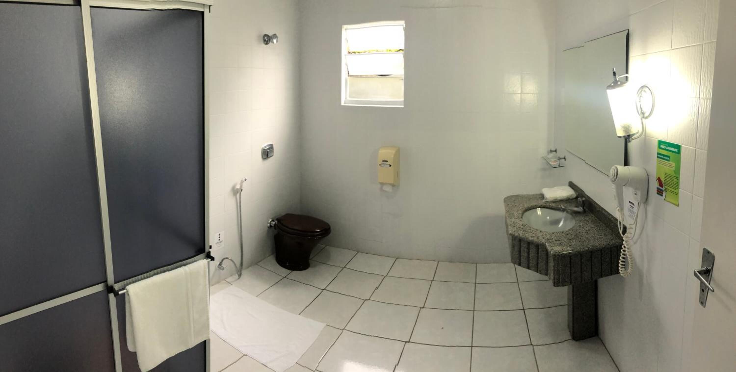 Ein kleines Badezimmer mit Toilette, Waschbecken und Spiegel. Ein Handtuchhalter und ein Fenster über der Toilette vorhanden.