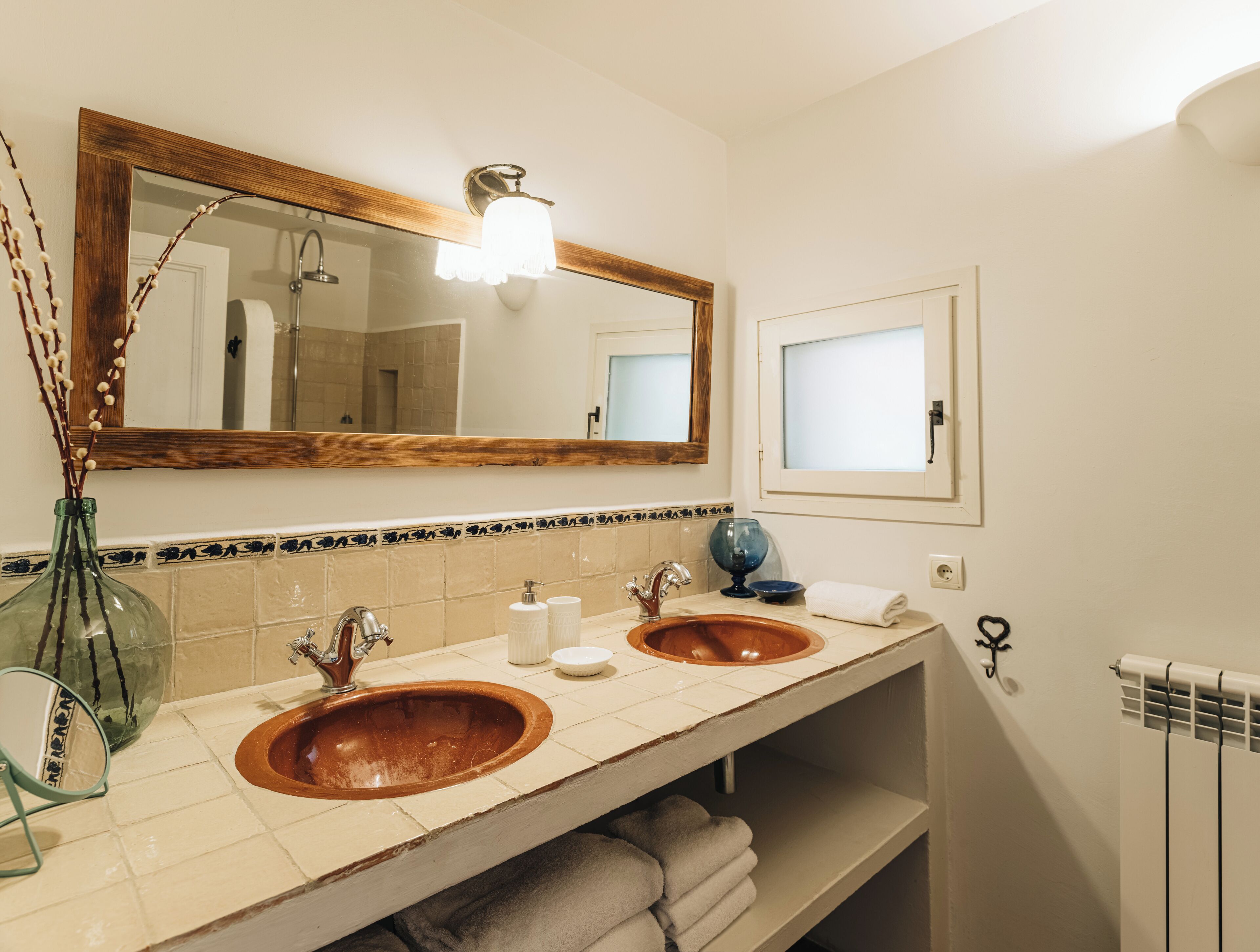 Une salle de bain avec deux lavabos, un grand miroir et un porte-serviettes.