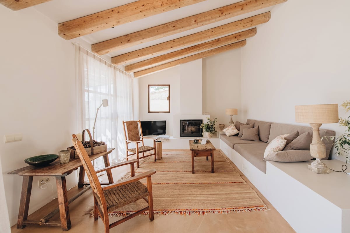 A cozy living room with a wooden ceiling, a sofa, a TV, and a dining area with chairs and a table.