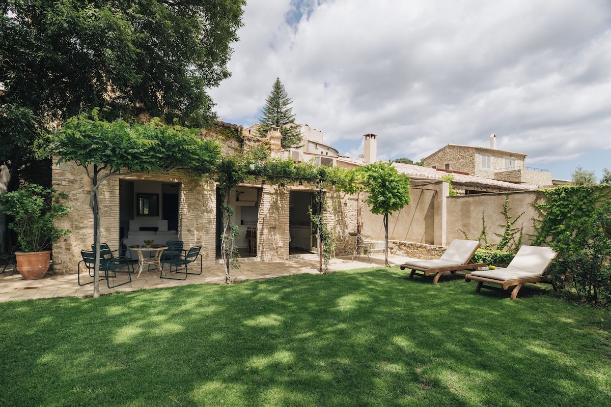 A stone building with a patio area, outdoor seating, and a well-maintained lawn.