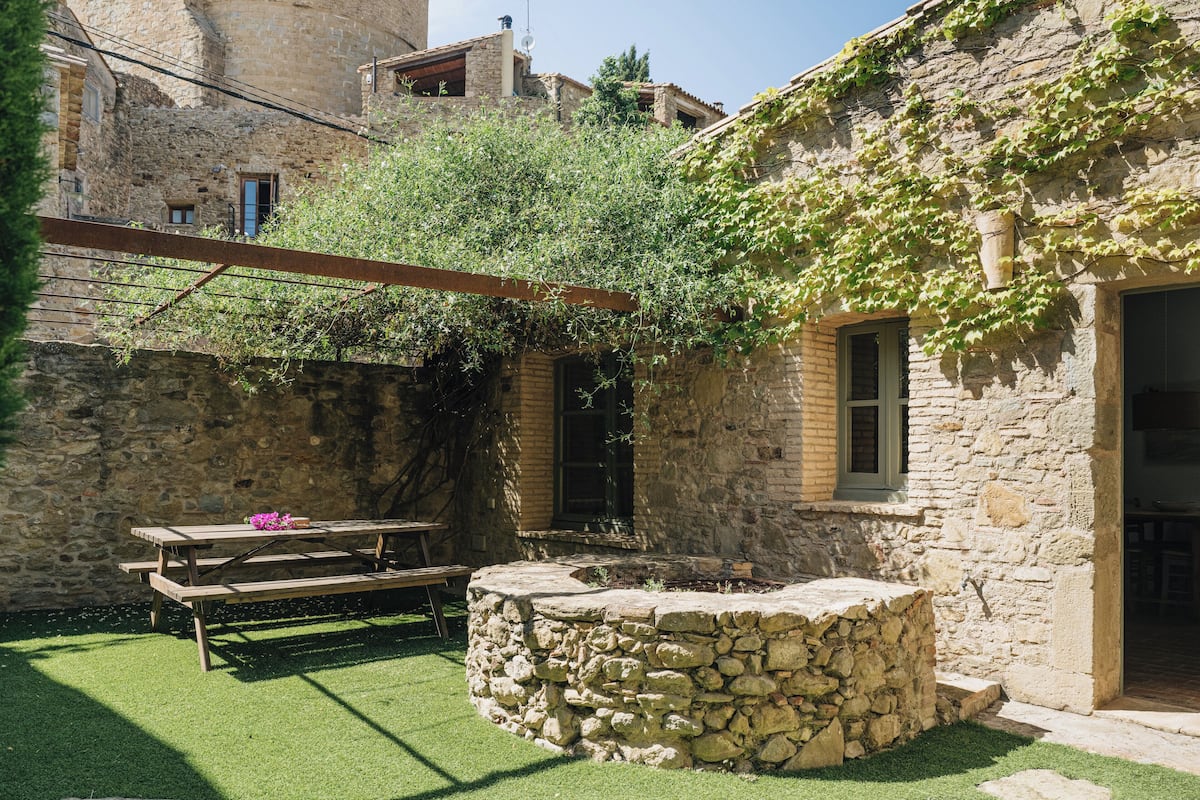 A stone building with ivy-covered walls, a stone bench, and a picnic table.
