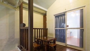 A wooden deck with a table and benches, a sliding glass door, and a brick floor. - Red Sun (Checheng)