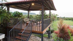 A covered outdoor deck with wooden furniture and a metal railing. - Red Sun (Checheng)