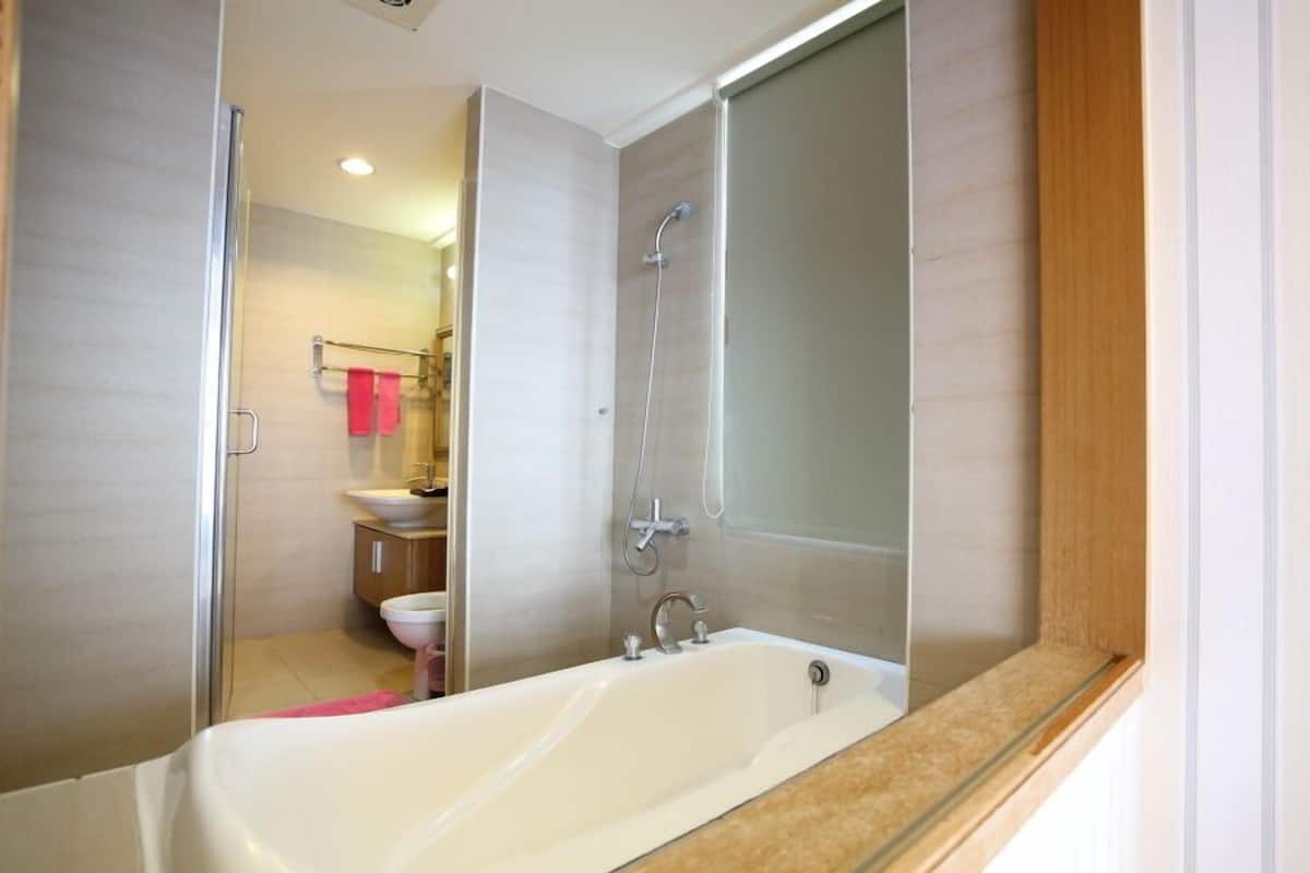 A modern bathroom with a bathtub, shower, and toilet.