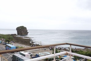 A coastal view with a prominent rock formation, a parking area with buses, and a clear sky. - Pin Ciao Hotel (Hengchun)