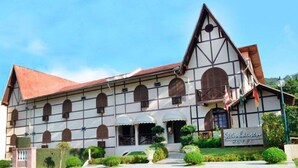 Un edificio tradicional con un techo empinado, varios ventanales en arco y un cartel que indica que es un hotel.