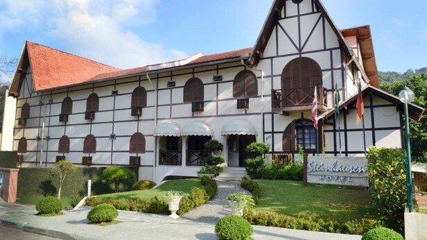 Un edificio tradicional con un techo empinado, varios ventanales arqueados y un letrero que indica que es un hotel.