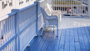 A deck with white railings and wicker chairs, overlooking a beach. - Sea View Inn (Old Orchard Beach)