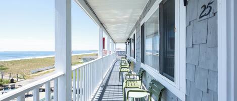 A balcony with a view of the beach, a pool, and numbered room 25.