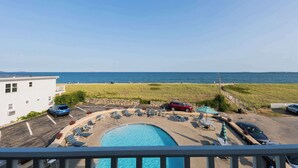 A pool area with lounge chairs, a swimming pool, and a view of the ocean. - Sea View Inn (Old Orchard Beach)