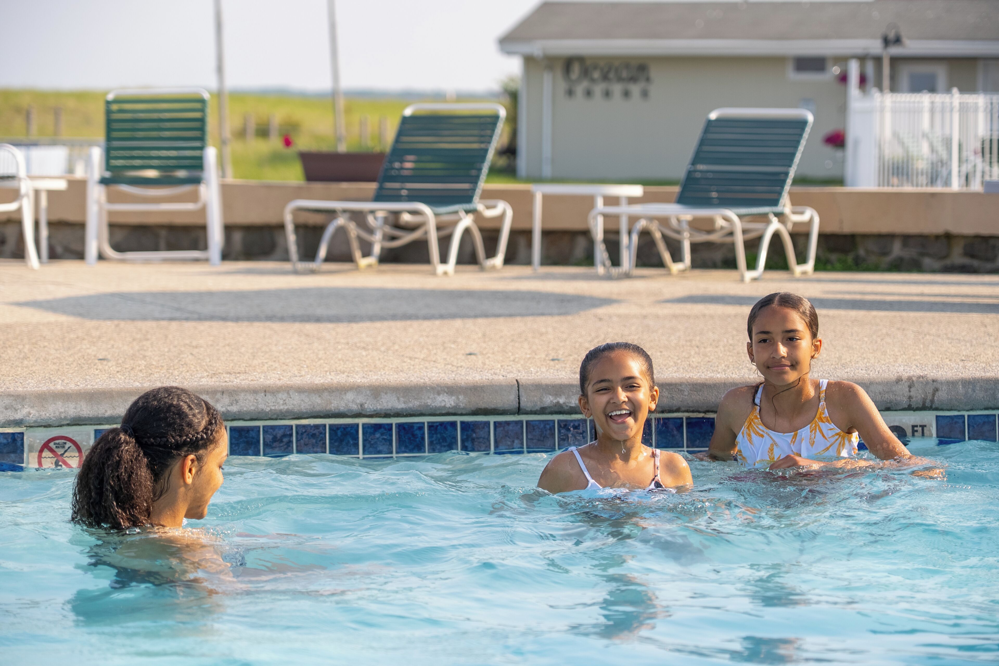 A swimming pool with lounge chairs and a building in the background.