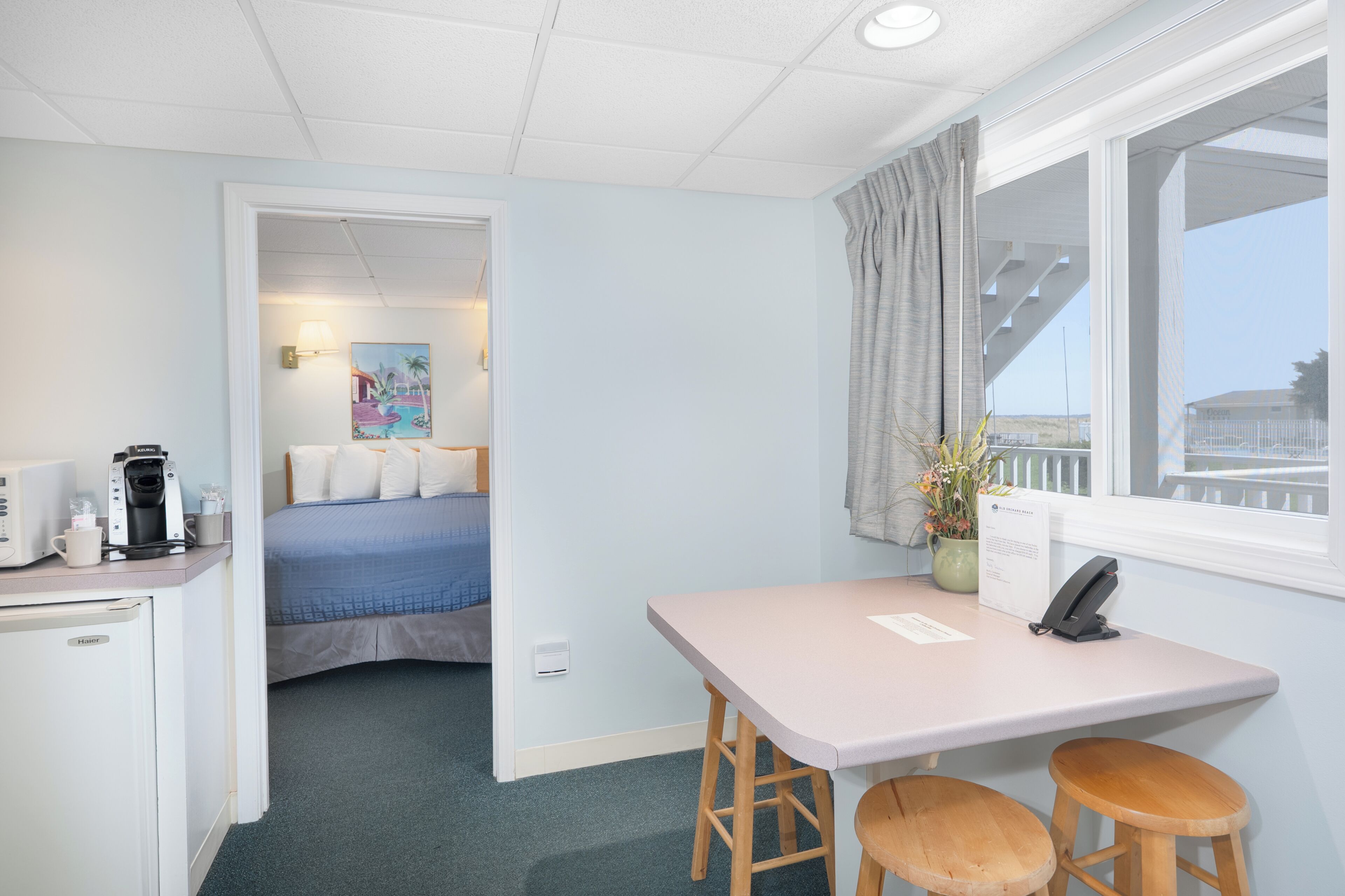 Une chambre d’hôtel avec un lit, un bureau avec un téléphone, une machine à café et une fenêtre donnant sur un paysage agréable.
