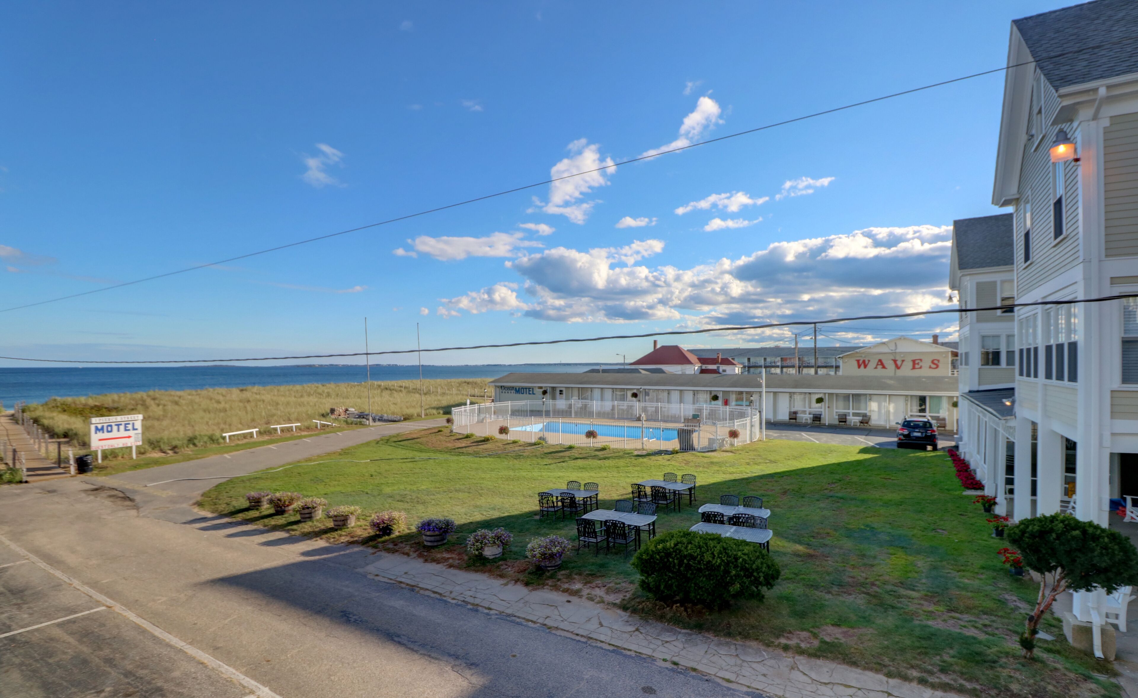A motel with a pool, outdoor seating, and a view of the ocean.