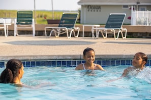 Une piscine avec des chaises longues et un bâtiment en arrière-plan.