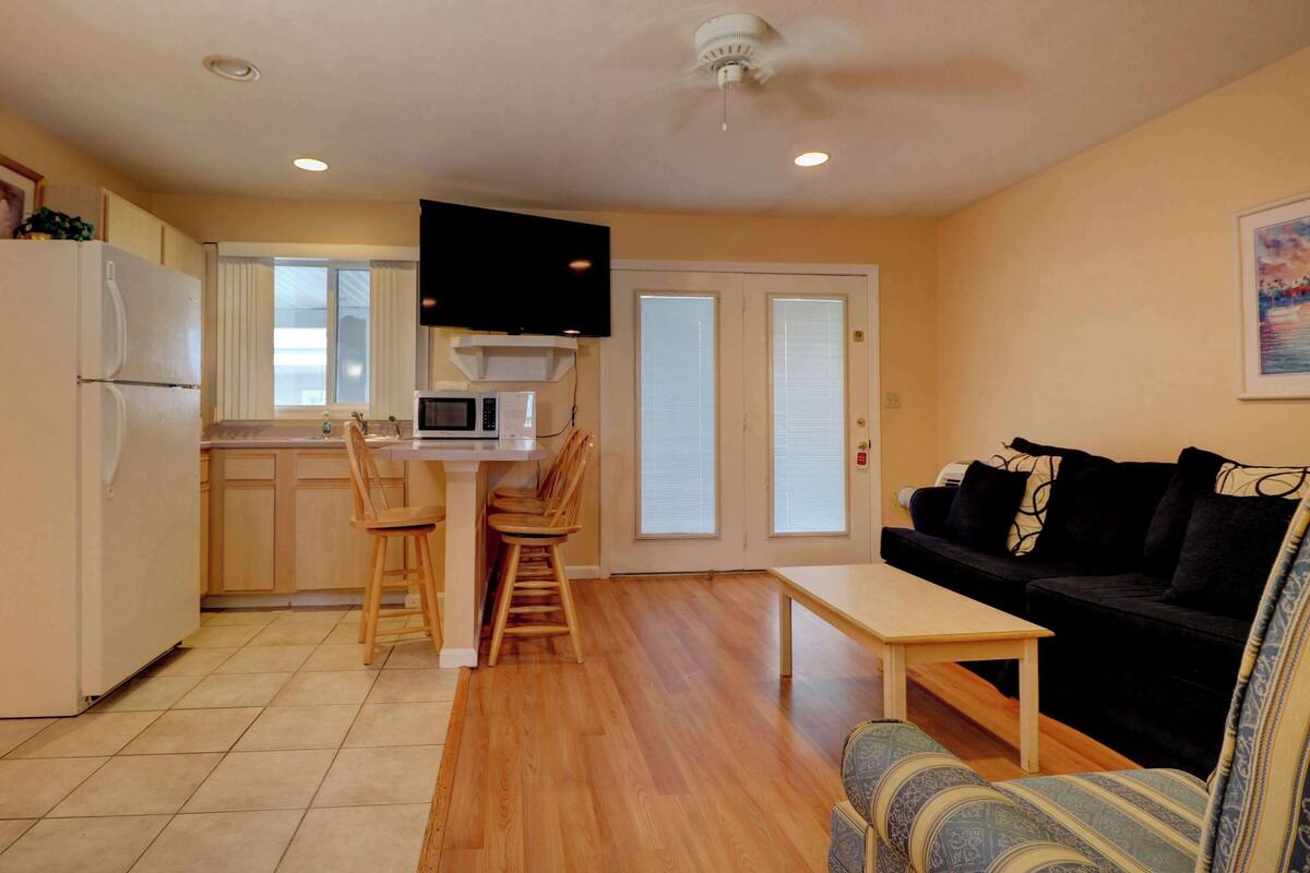 A compact living space with a kitchenette, a dining area, and a seating area with a sofa and chairs.