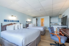 Une chambre d’hôtel avec deux lits, un bureau, une chaise et une kitchenette.
