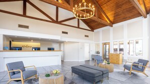 A spacious lobby with a reception desk, seating area, and a high ceiling with exposed beams. - Sea View Inn (Old Orchard Beach)