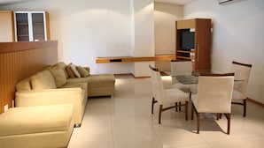 Un salon moderne avec un canapé, une table à manger et des chaises, et un téléviseur fixé au mur.