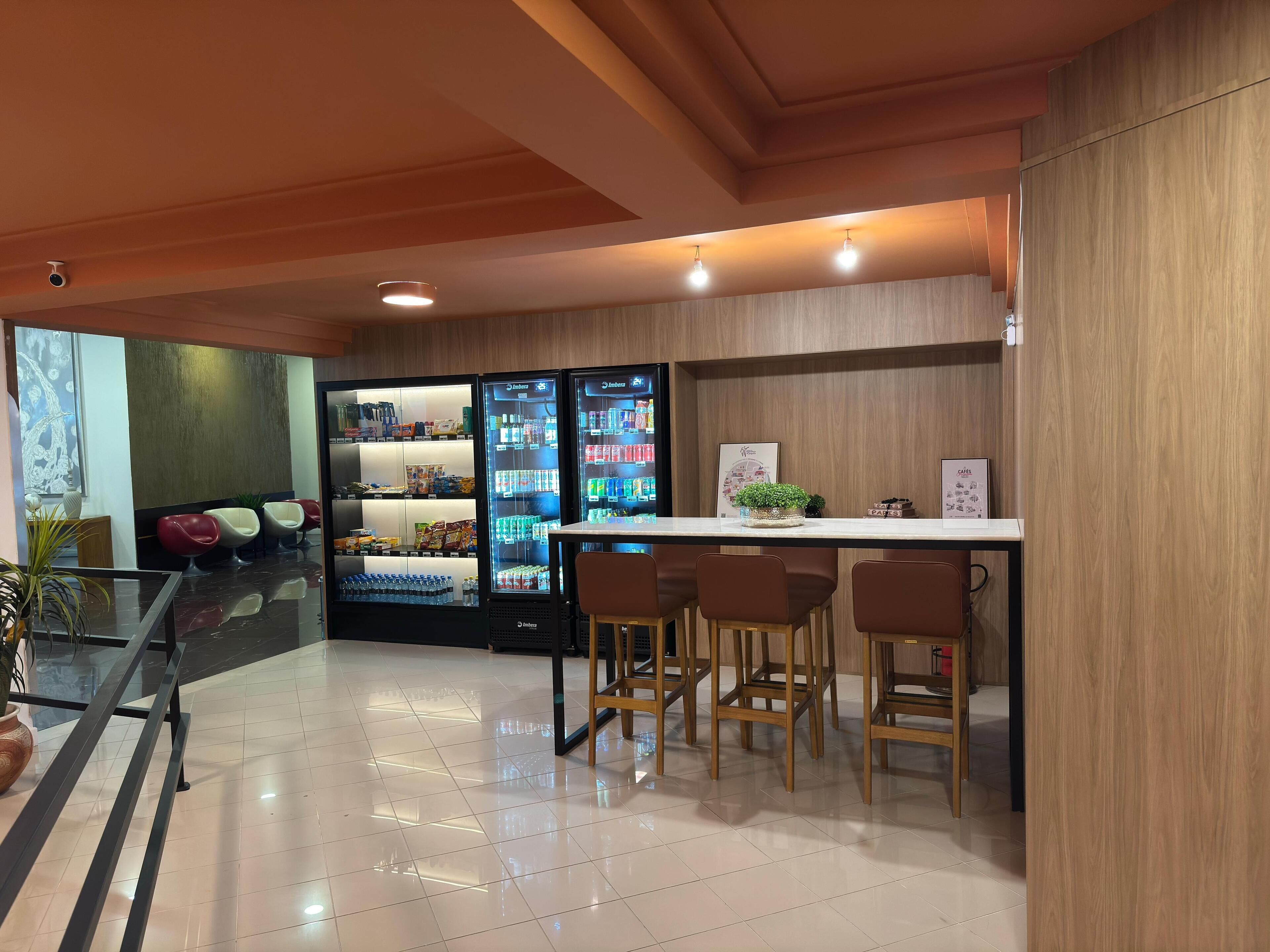 Eine moderne Bar mit einer Theke, Sitzgelegenheiten und einem mit Getränken gefüllten Kühlschrank.