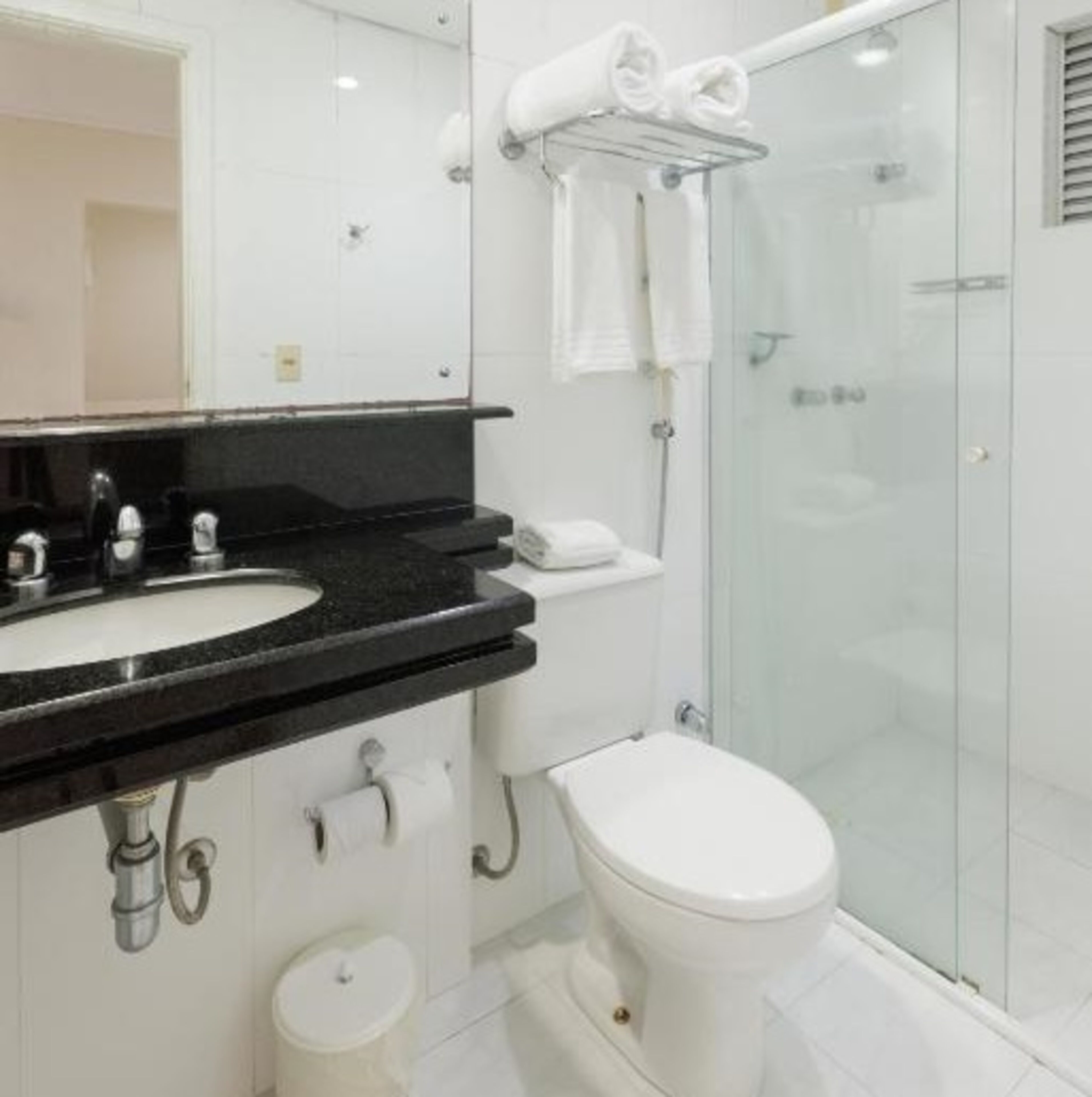 Un bagno moderno con lavabo su piano nero, un water e un box doccia in vetro.