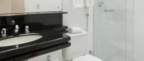 Un bagno moderno con lavabo su piano nero, un water e un box doccia in vetro.
