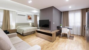Une chambre d’hôtel moderne équipée d’un lit, d’une télévision, d’un bureau et d’un canapé.