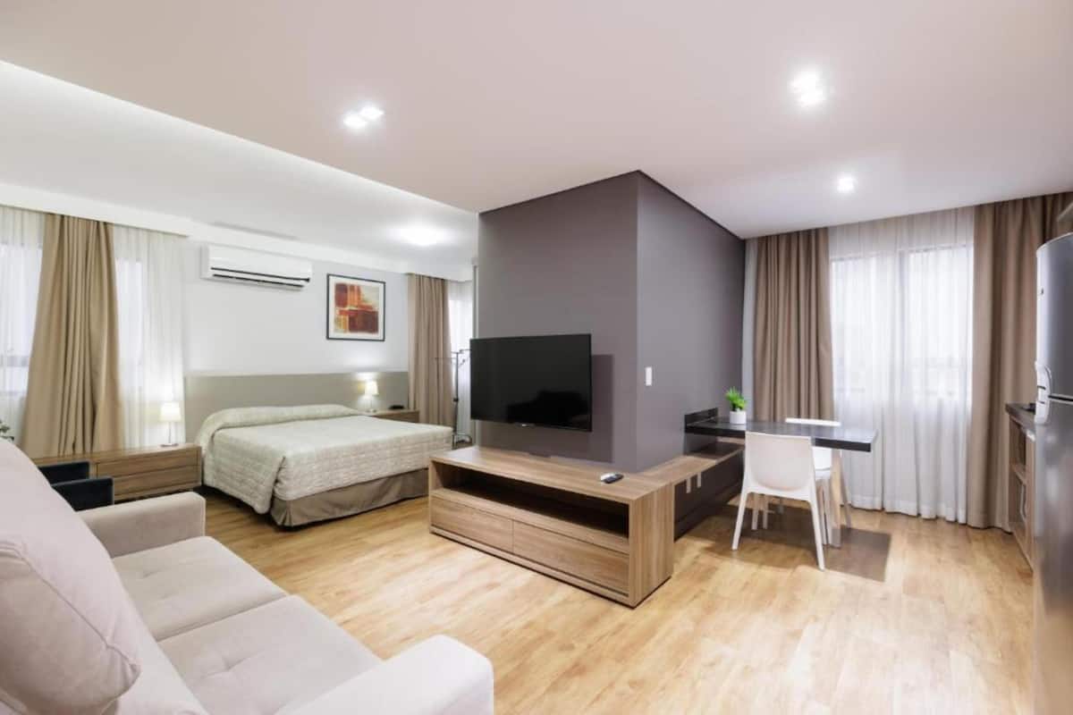 Een moderne hotelkamer met een bed, een televisie, een bureau en een bank.