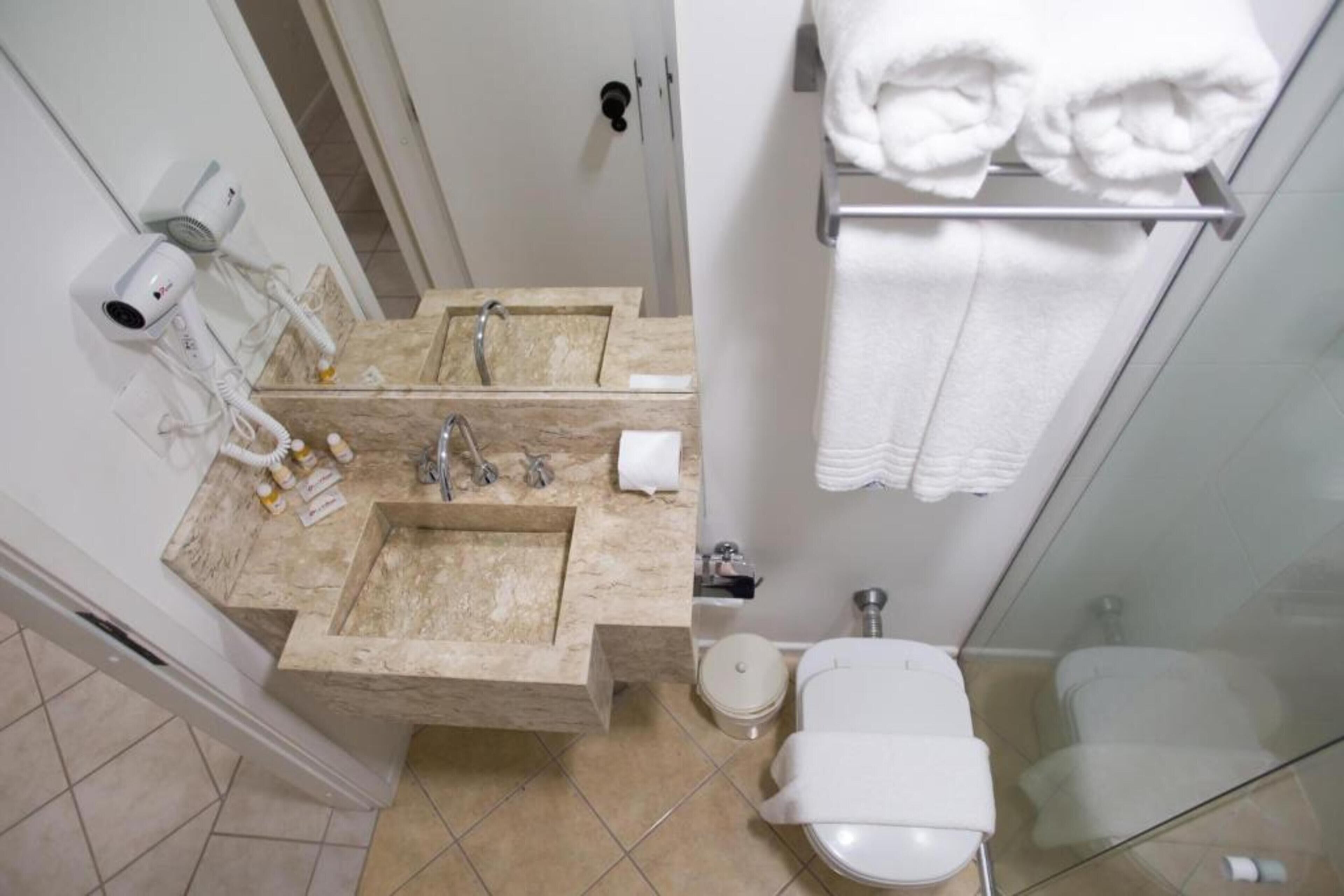 Un baño con dos lavamanos, un inodoro y una cabina de ducha de vidrio.