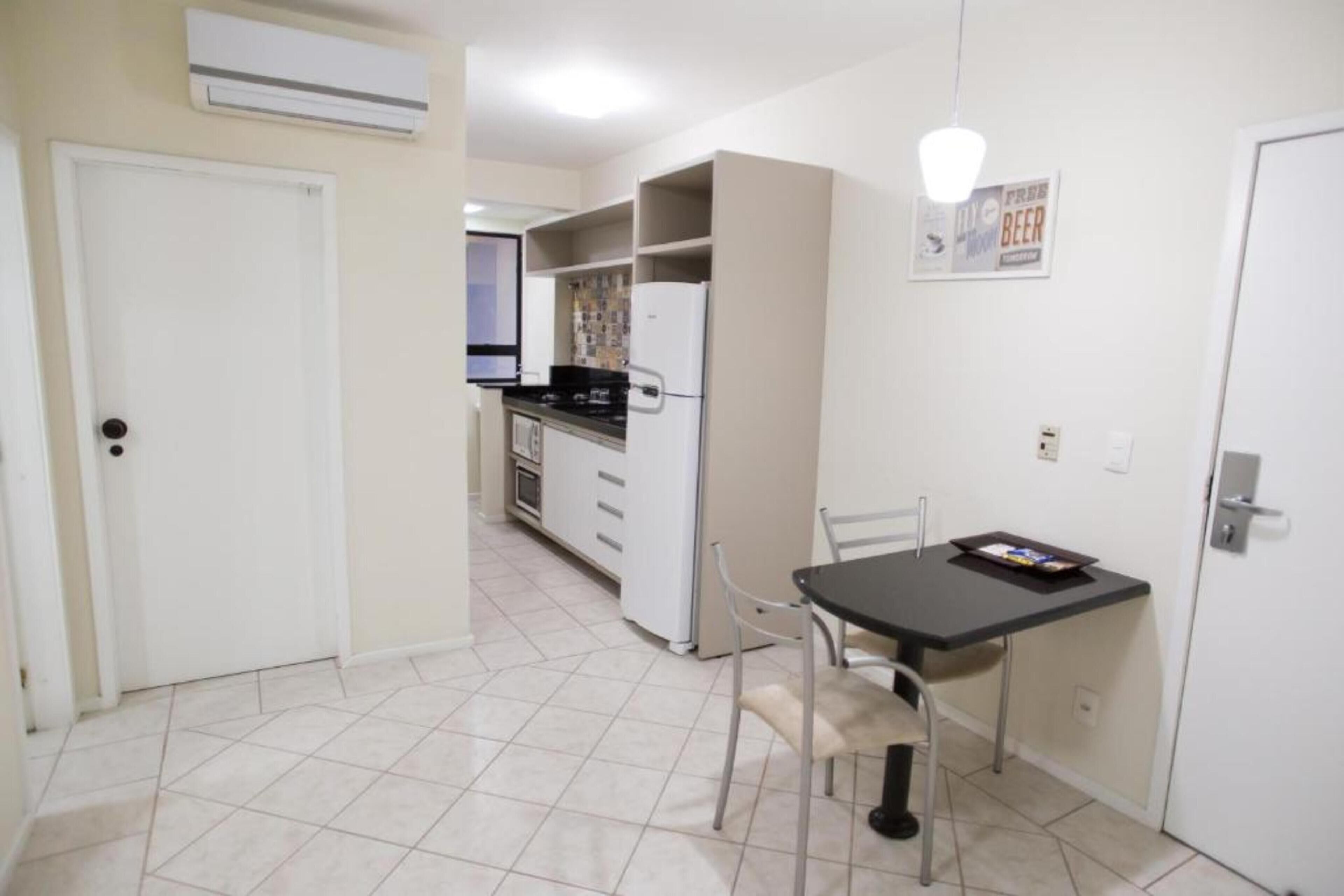 A compact kitchen with a dining area, a refrigerator, and a small table with chairs.