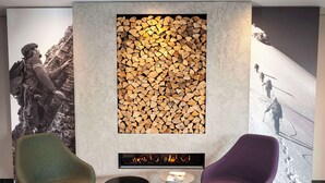 Un área de estar moderna con chimenea, dos sillones y una mesita.