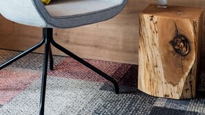 A modern room with a grey upholstered armchair, a yellow pillow, a white vase with flowers, and a wooden side table. - Best Western Hotel The K Munich Unterfoehring (Unterfoehring)