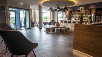 Eine moderne Lobby mit Empfangsbereich, Sitzgelegenheiten und einer Bar.