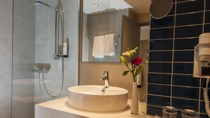 A modern bathroom with a glass-enclosed shower, a round sink, and a large mirror. - Best Western Hotel The K Munich Unterfoehring (Unterfoehring)