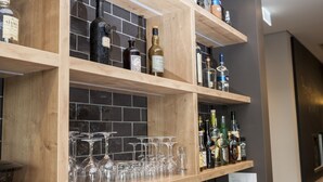 Una zona de bar con estantes de madera que sostienen botellas y vasos.
