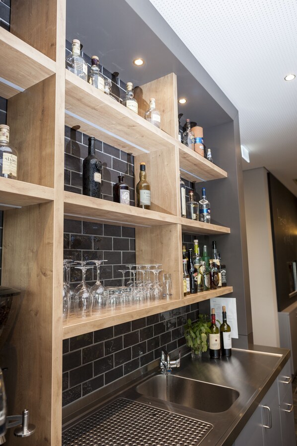 A bar area with wooden shelves holding bottles and glasses. - Best Western Hotel The K Munich Unterfoehring (Unterfoehring)
