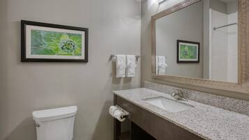 Une salle de bain avec des toilettes, un lavabo et un miroir. Des tableaux encadrés ornent le mur.