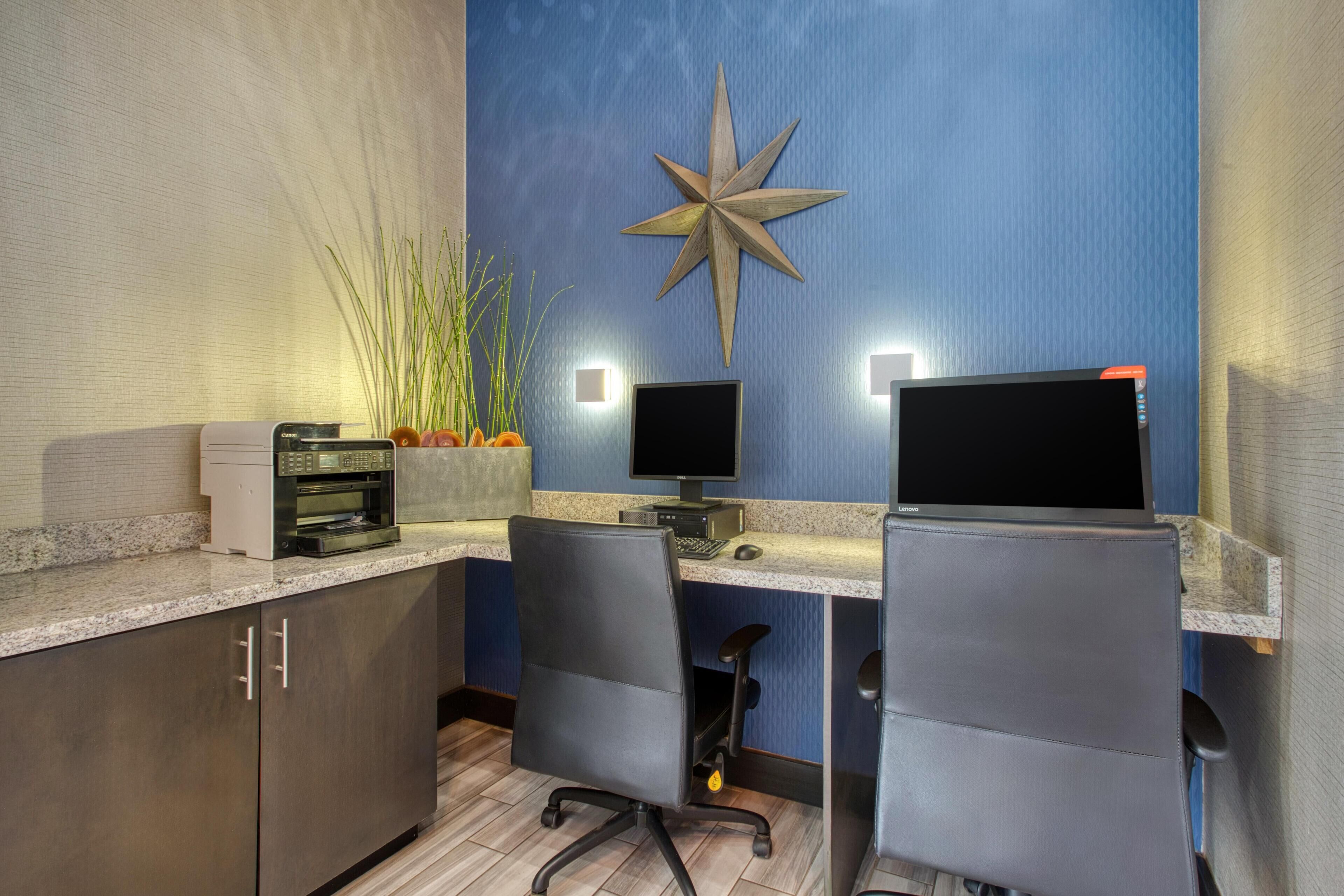 A modern kitchen with granite countertops, a built-in oven, and a microwave. There are two black office chairs and a large star-shaped wall decoration.