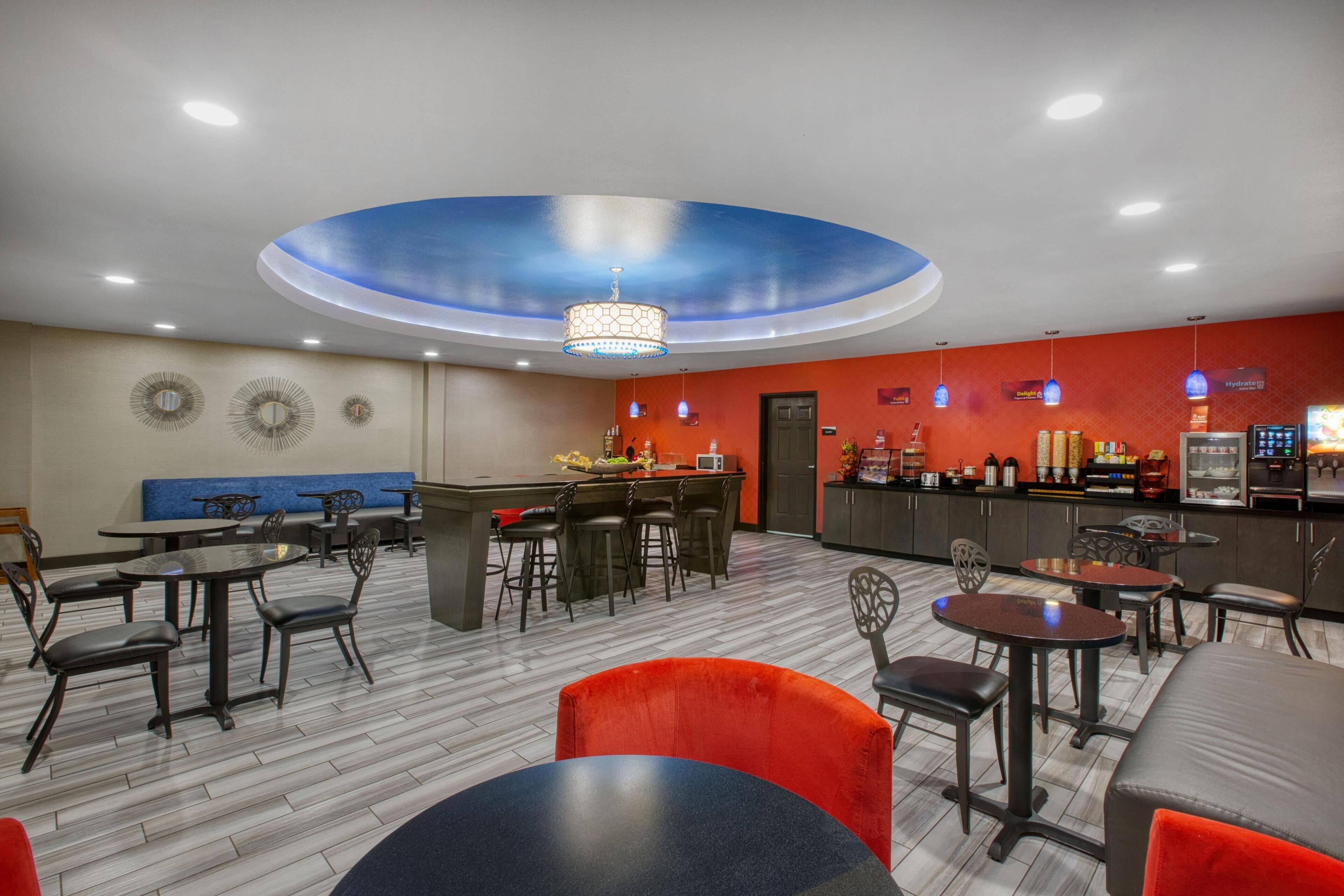 Un restaurante moderno con barra central, varias zonas de estar y un diseño de techo distintivo.