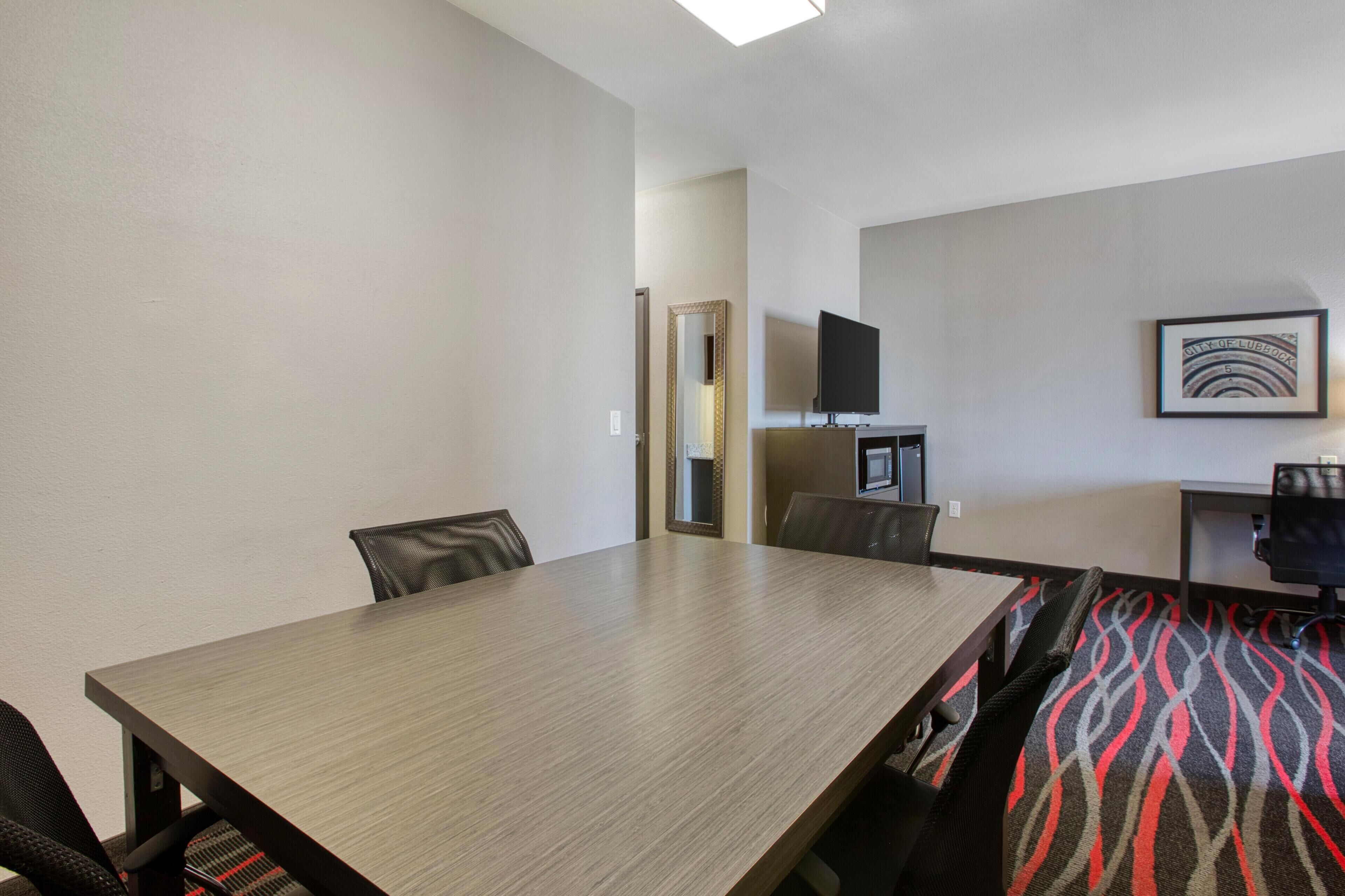 Une salle de conférence avec une longue table, des chaises, un téléviseur et un tableau encadré au mur.