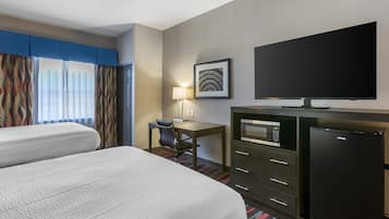 Une chambre d’hôtel avec deux lits, un bureau avec une chaise, une télévision, un four à micro-ondes et un réfrigérateur.