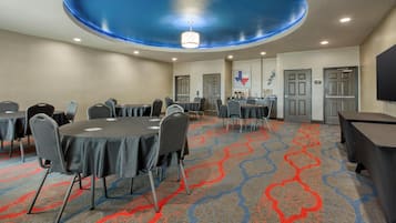 A conference room with round tables, chairs, and a blue ceiling design.