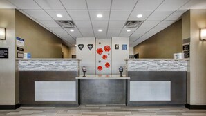 Een receptiezone met een modern ontwerp, met een receptiebalie, een informatiebord aan de muur en een vloer met een patroon.