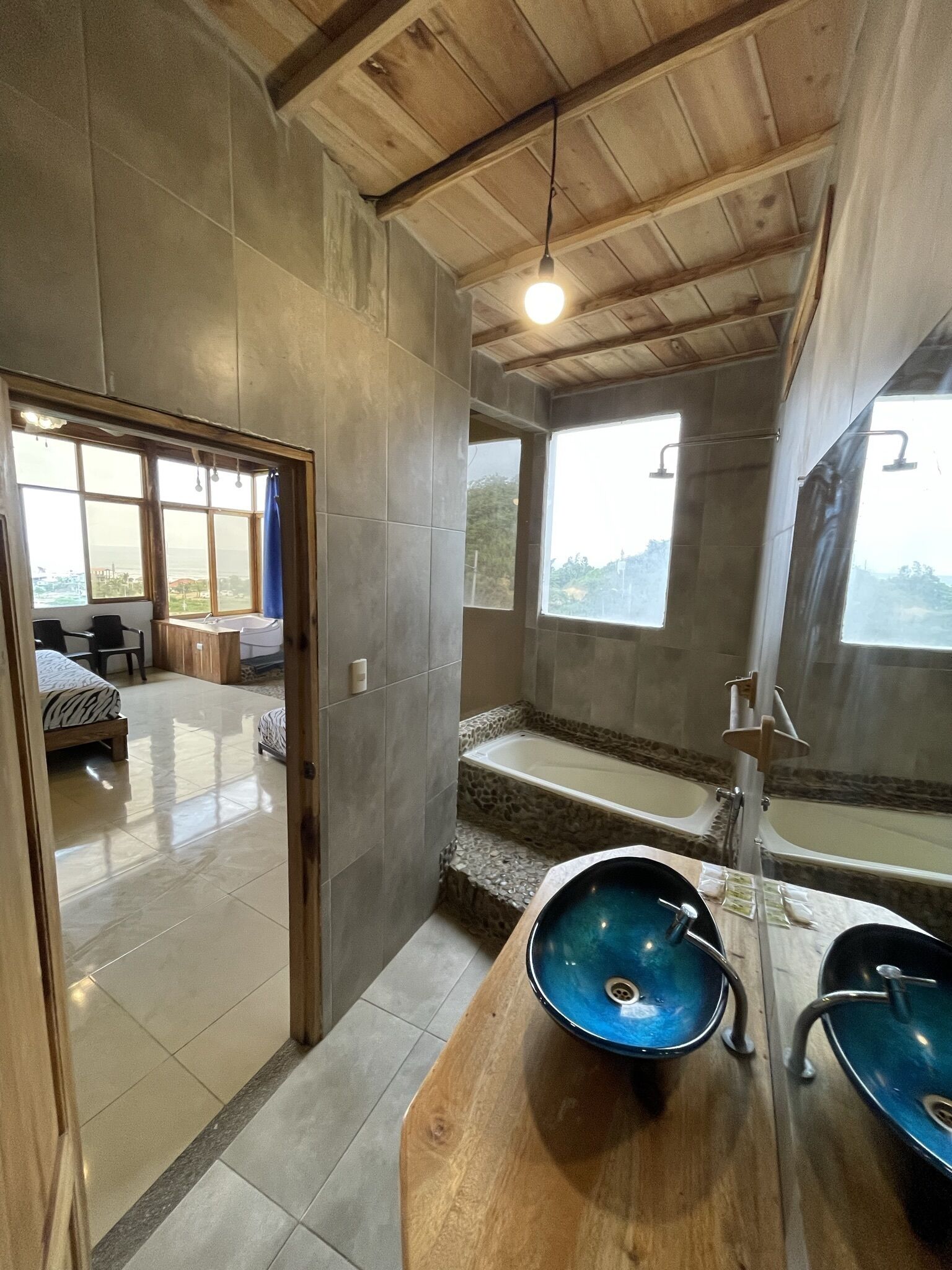 A modern bathroom with a bathtub, a large mirror, and a wooden vanity with a blue basin.