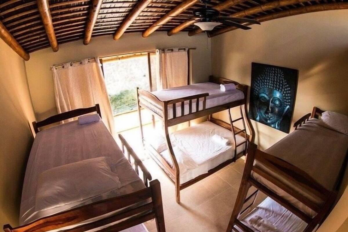 Une chambre avec des lits superposés, un ventilateur de plafond et un tableau représentant un Bouddha.