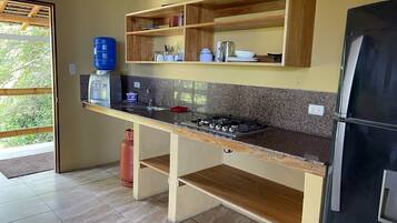 A kitchen with a granite countertop, wooden cabinets, a gas stove, and a black refrigerator.