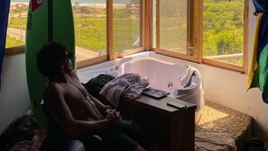 Ein Zimmer mit einem großen Fenster, einer Badewanne und einem Surfbrett.