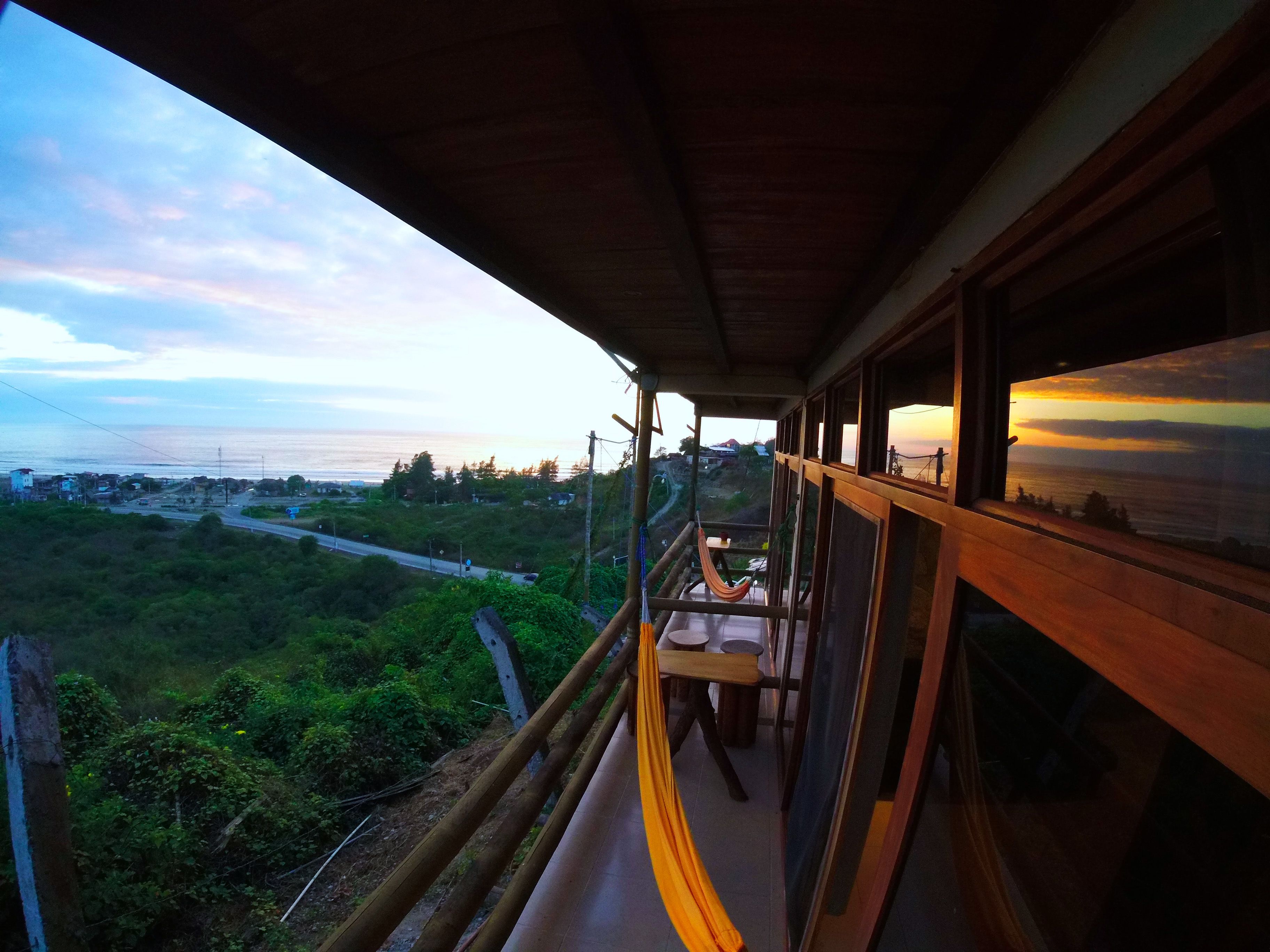Un balcón con vista al océano y al atardecer.