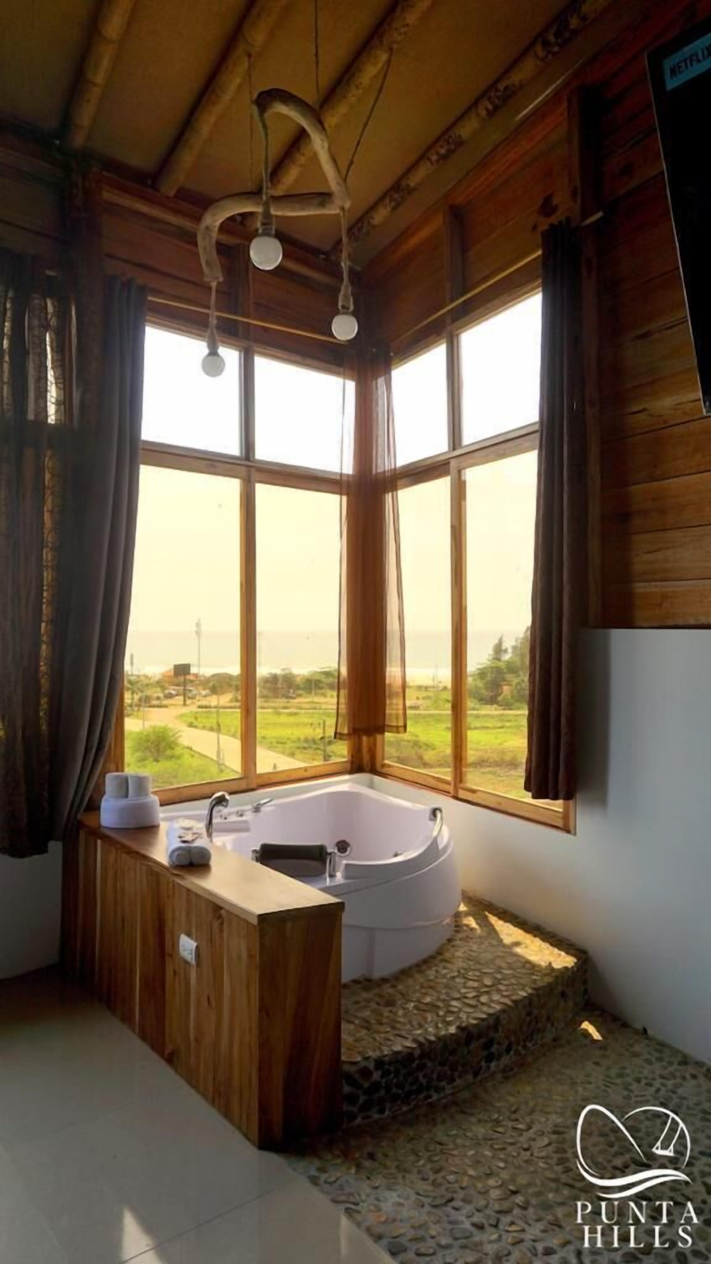 A bathroom with a large window, a bathtub, and a wooden vanity.
